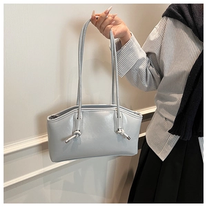 Detail of light blue faux leather tote with knotted straps and polished texture