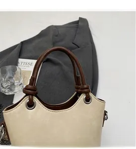 Détail du sac seau en similicuir crème avec anse nouée marron et coutures de précision
