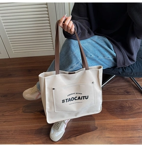 Detail of canvas tote bag with brown leather handles and coherent design lettering