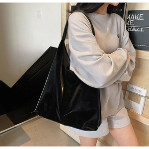 Close-up of black glossy leather tote bag showing reflective finish and wide strap