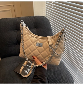 Nahaufnahme der beigen Stepptasche mit silberner Kette und Metallschloss-Verschluss