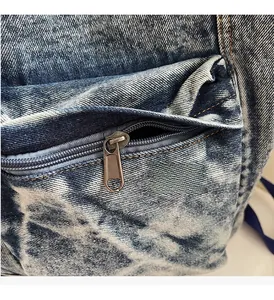Detail view of smooth metal zipper and stonewashed denim texture on large backpack