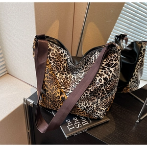 Close-up of leopard print tote bag with black leather base and wide nylon strap