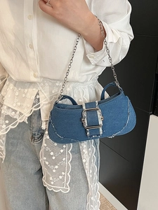 Blue denim shoulder bag with silver chain and metal buckle on a model in a modern room