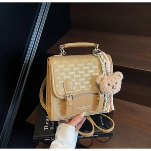 Détail du sac à main vintage en cuir camel avec breloque ours sur des livres d'art