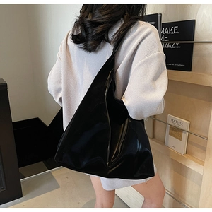 Close-up of a large black glossy tote bag with a smooth finish in a boutique setting