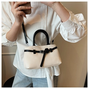 Close-up of cream woven bucket bag with black leather straps and top handle on a model