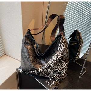 Detail of a glossy leopard print tote bag with wide brown strap for daily commuting