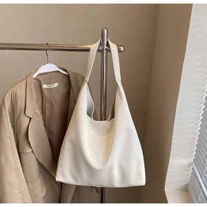 Detail view of a large cream leather tote bag paired with a beige blazer for a minimalist look