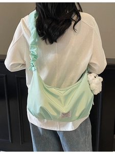 Large mint green dumpling shoulder bag with ruched strap and white plush pendant accessory