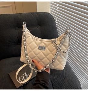 Detail der weißen gesteppten Hobo-Tasche mit silbernem Drehverschluss und Kettenriemen