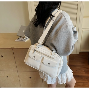 Close-up of retro white leather tote bag with silver snaps and wide shoulder strap detail
