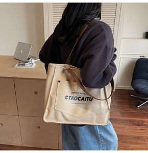 Detailed back view of a large beige canvas tote bag with brown straps in an office setting