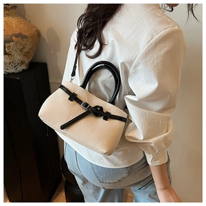 Detail of a beige woven bucket bag with black round handle and leather strap buckle
