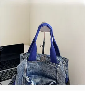 Detail of denim backpack with durable royal blue handles and dual metal zippers