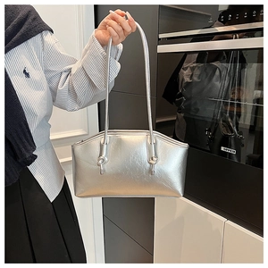 Detail of silver metallic tote bag featuring dual long straps and knot metal accents
