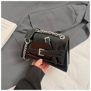 Detailed view of black patent leather crossbody bag with silver buckles and chain strap