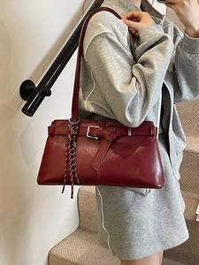 Fashionable burgundy underarm bag with metal buckle strap and woven pendant charm