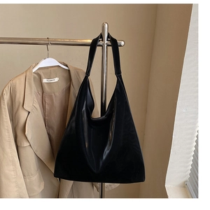Detail of glossy black patent leather tote bag with mirror finish on metal hanger