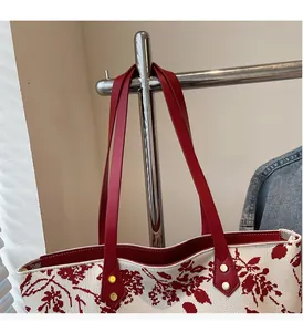 Detail of red floral tote bag with sturdy leather handles and golden rivet reinforcements