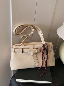 Minimalist beige underarm bag with decorative braided rope and metallic belt buckle detail
