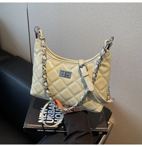 Detail der beigen gesteppten Ledertasche mit silbernem Drehverschluss und Kettenriemen