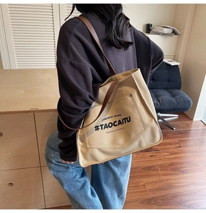 Detail of canvas tote bag with brown leather straps and front pocket for commuting