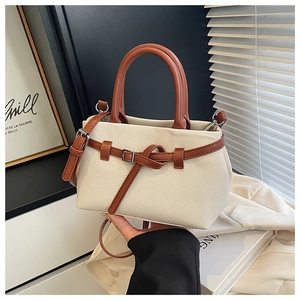 Close-up of beige woven texture bucket bag with brown leather handles and metal buckle