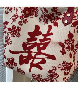 Close-up of knit tote bag featuring red Double Happiness character and leather handle