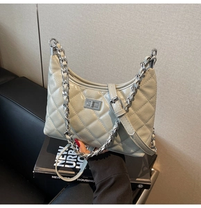 Detailansicht der grauen Stepptasche mit silberner Kette und Metall-Drehverschluss-Detail