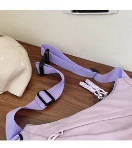 Detail of adjustable shoulder strap and woven zipper pull on casual purple crossbody bag