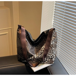 Detail of leopard print tote bag with brown wide shoulder strap on a sofa