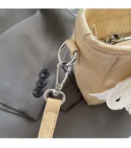 Détail d'un sac à main beige en cuir plissé avec boucles argentées et bordure en dentelle