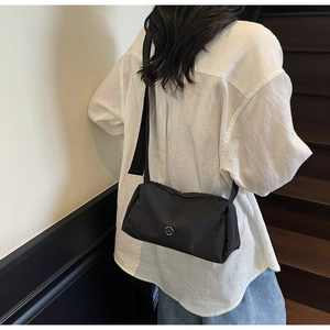 Detailed side view of black nylon crossbody bag with wide shoulder strap on a model