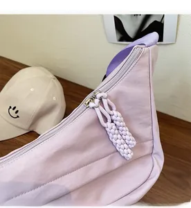 Detail view of the smooth zipper closure on this lavender nylon crossbody bag
