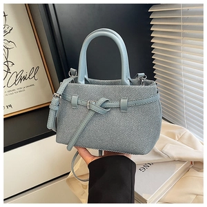 Close-up of light blue knitted texture bucket bag with leather strap and silver hardware