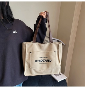 Close-up of beige canvas tote bag featuring reinforced pocket and elegant handle detail