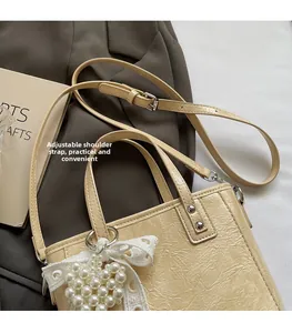 Détail du sac seau beige avec bandoulière réglable et pendentif cœur en perles