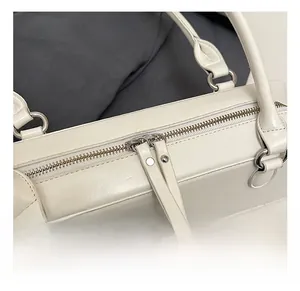 Close-up of white baguette bag showing dual silver zippers and premium metal hardware
