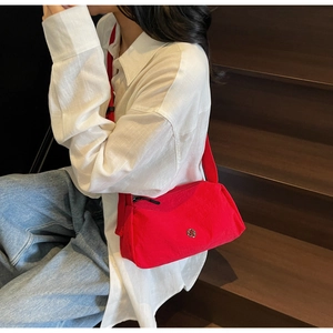 Close-up of red nylon crossbody bag with metallic logo detail on a female model