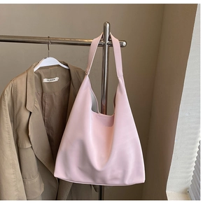 Detail of pink large-capacity faux leather hobo bag hanging beside a blazer