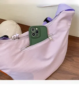 Detail of light purple nylon crossbody bag showing spacious front zipper pocket for phone