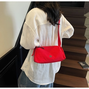 Detail of red nylon crossbody bag showing the premium texture and metal logo plaque