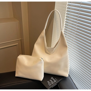 Minimalist white leather hobo tote bag set with matching pouch on a black chair