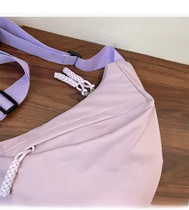 Close-up of purple nylon crossbody bag with letter embroidery and braided rope zipper