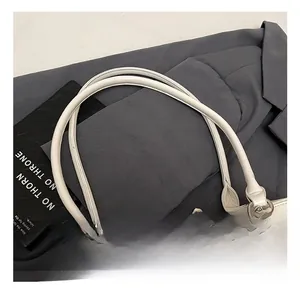 Detail showing smooth cylindrical leather handles and elegant cream bow on the handbag