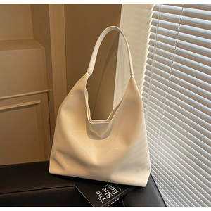 Macro view of beige leather tote bag on sofa with shadows from window blinds
