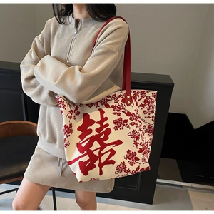 Detail of red wedding double happiness character and golden rivets on beige tote bag