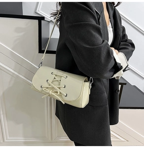 Detailed side view of off-white PU leather crossbody bag with lace-up ribbon design