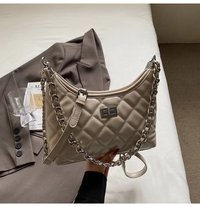 Detail der beigen gesteppten Hobo-Tasche mit Metalldrehverschluss und zwei Riemen